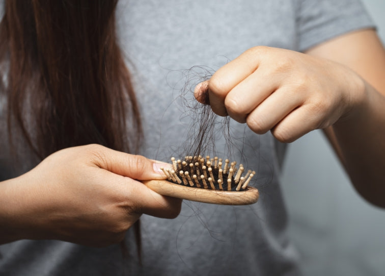 Lady pulling hair loss from brush