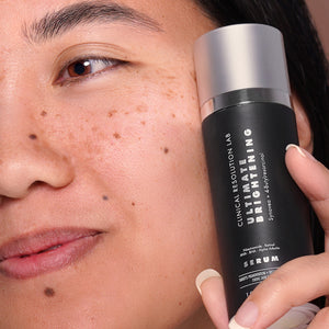 ultimate brightening serum in hand of model next to face