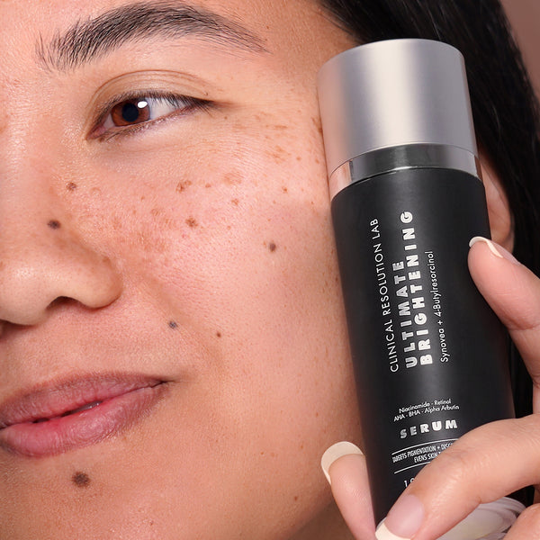 ultimate brightening serum in hand of model next to face