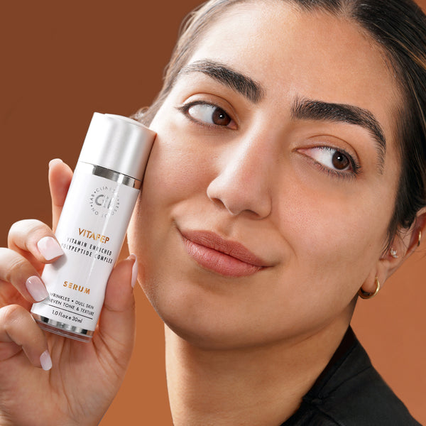Vitapep serum in hand of model with brown background