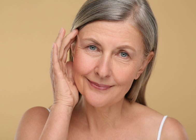 women touching face with blue eyes and beige backhground
