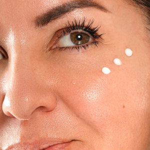 Close-up of a woman's face with skincare product application on cheek