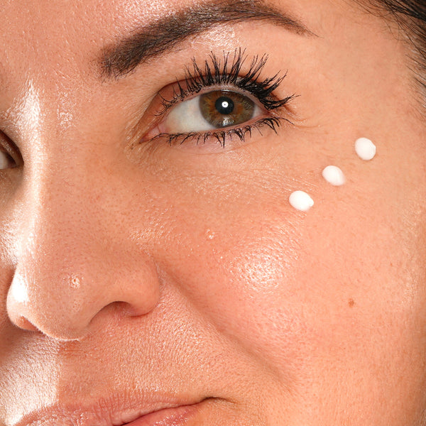 Close-up of a woman's face with skincare product application on cheek